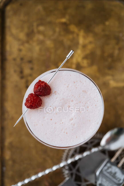 Vue de dessus de cocktail d'alcool rouge coloré dans un verre élégant sur la table avec cuillère de bar et passoire dans le restaurant — Photo de stock