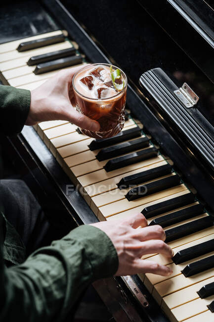 De cima de homem sem rosto tocando piano com um e e segurando vidro com coquetel i outra mão — Fotografia de Stock