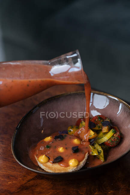 Сверху стильная керамическая чаша с жареными ломтиками помидоров картофеля и нежной котлеткой, наливающейся красным соусом из стеклянной банки в ресторане — стоковое фото