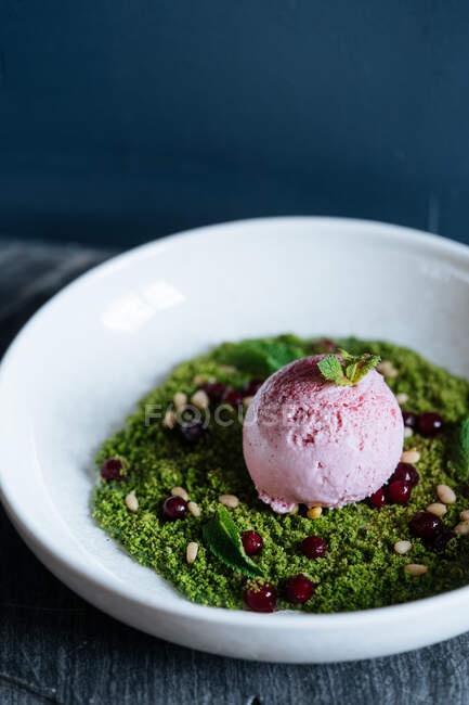 Dall'alto di misurino di gelato viola su mousse verde decorata con noci e menta fresca in ciotola bianca — Foto stock