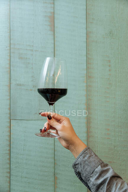 Von unten der Ernte weibliche Hand mit stilvollem Glas Rotwein mit modernen Interieur des Restaurants — Stockfoto