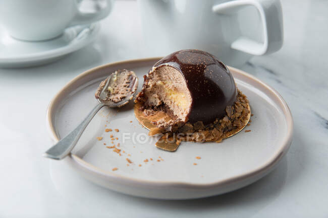 Верхня кухня кондитерський продукт вершкового мусу в шоколаді, прикрашений крупами на тарілці з ложкою — стокове фото