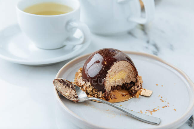 Haute cuisine confectionery product of creamy mousse in chocolate decorated with cereals on plate with spoon — Stock Photo