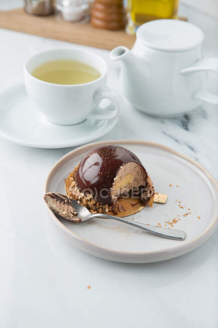 Кондитерские изделия высокой кухни из сливочного мусса в шоколаде, украшенные злаками на тарелке с ложкой — стоковое фото