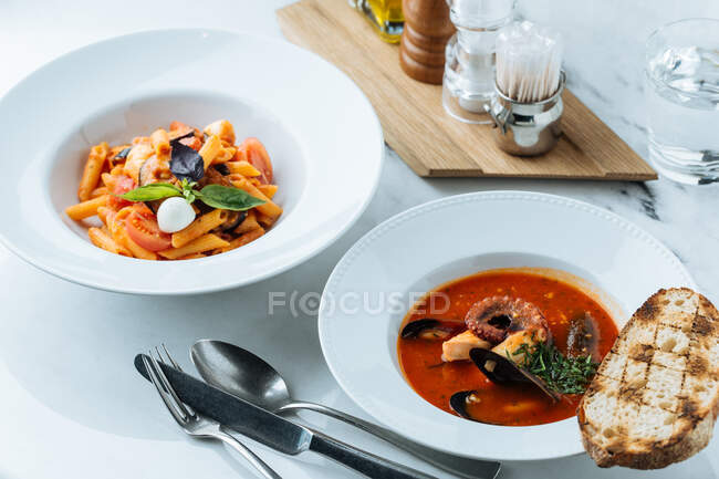 From above of tasty pasta with fresh pieces of tomato and eggplants decorated with basil leaves and sauce in restaurant — Stock Photo