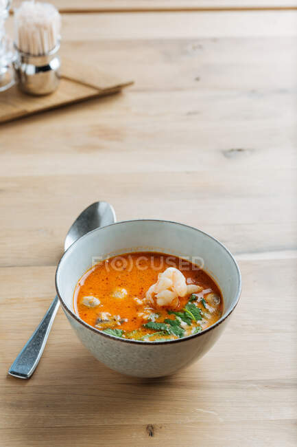 Von oben würzige Suppen-Delikatesse mit Garnelen und Grün in Keramikschüssel auf Tisch mit Metalllöffel — Stockfoto