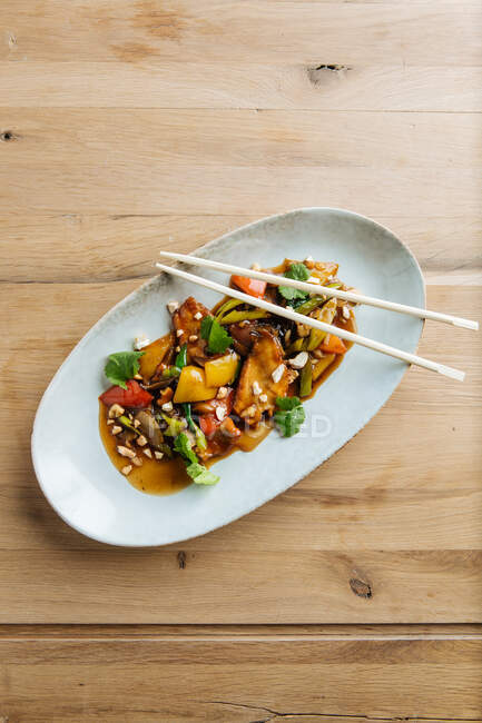 Вид сверху слайсов цветных овощей и мяса на овальной тарелке с деревянными палочками — стоковое фото