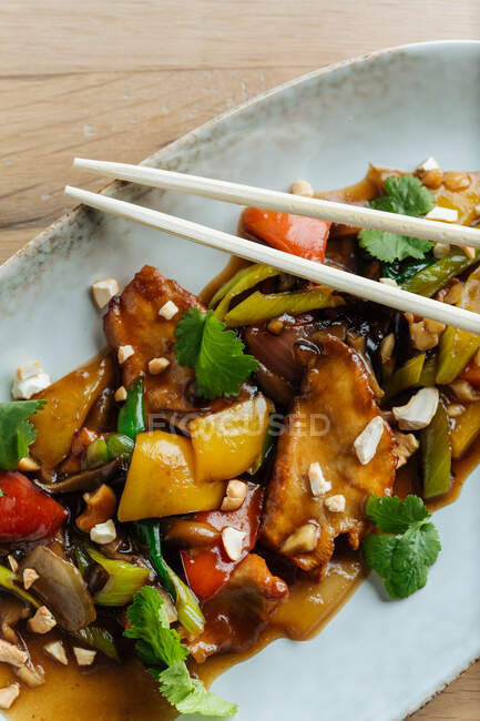 Вид зверху на скибочки барвистих овочів і м'яса на овальній тарілці з дерев'яними паличками — стокове фото