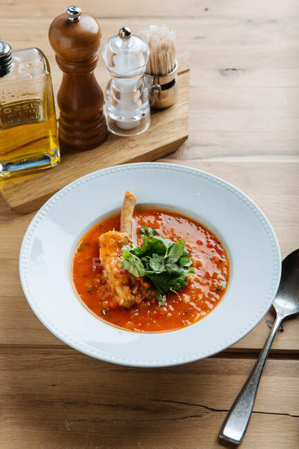 Вид сверху на красный суп с мясом и свежей зеленью на деревянном столе в ресторане — стоковое фото