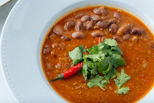 Closeup from above of tasty red soup with red hot chili pepper beans and parsley in restaurant — Stock Photo