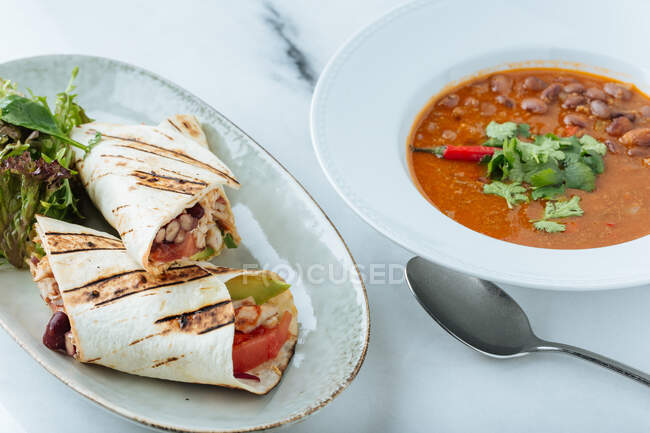 De cima de sopa com feijão salsa fresca e giroscópios com legumes e carne na mesa no restaurante — Fotografia de Stock