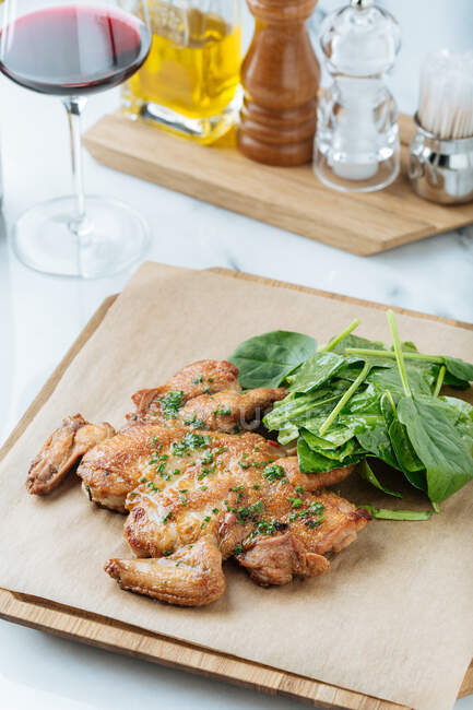 Du dessus du poulet doré frit et des herbes sur une planche de bois avec des feuilles de basilic au restaurant — Photo de stock