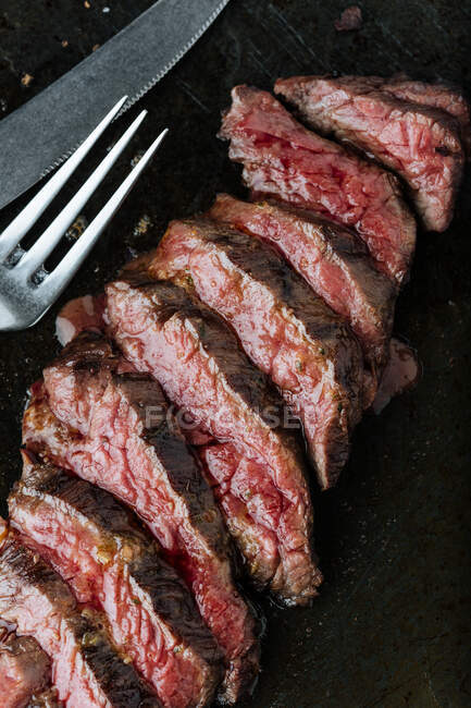Top view of medium rare slices steak on table with fork and knife in restaurant — Stock Photo
