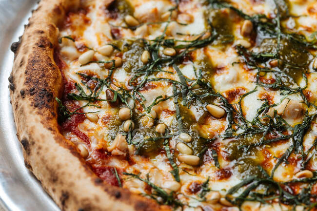 De haut de pizza végétarienne au four juteuse servie avec du fromage, des graines et des herbes sur la table dans le restaurant — Photo de stock
