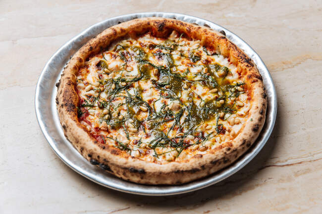 De cima de pizza vegetariana assada suculenta servida com queijo, sementes e ervas na mesa no restaurante — Fotografia de Stock