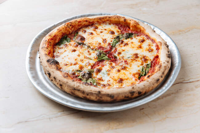 Зверху соковита запечена піца, яку подають з сиром і травами на столі в ресторані — стокове фото