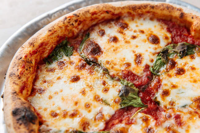 De dessus de pizza au four juteuse servie avec du fromage et des herbes sur la table dans le restaurant — Photo de stock