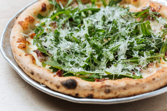 Close-up de cima de pizza cozida no forno saborosa decorada com arugula verde e queijo ralado no restaurante — Fotografia de Stock