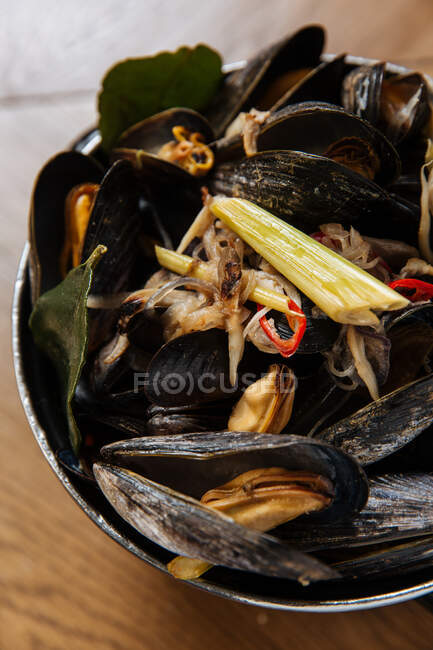 Вид зверху на чорну страву з молюсками з різноманітними овочами на пару в чорному горщику на столі — стокове фото