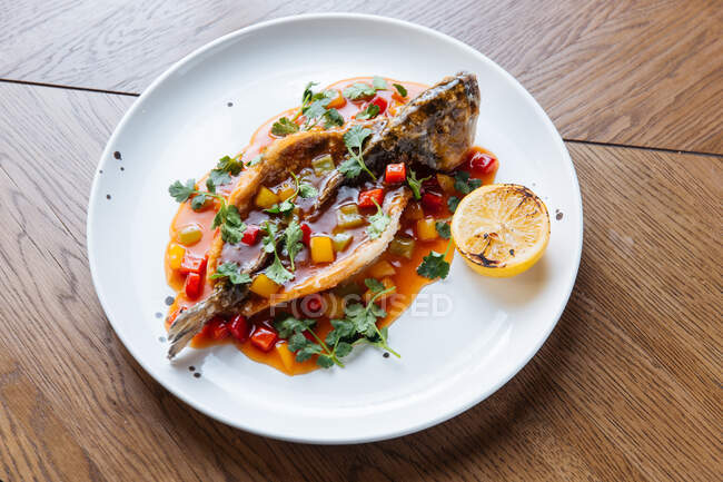 Von oben von ganz gebratenem Weißfisch geschnitten und mit Tomatensauce und Gemüse gefüllt, garniert mit grünem Koriander — Stockfoto