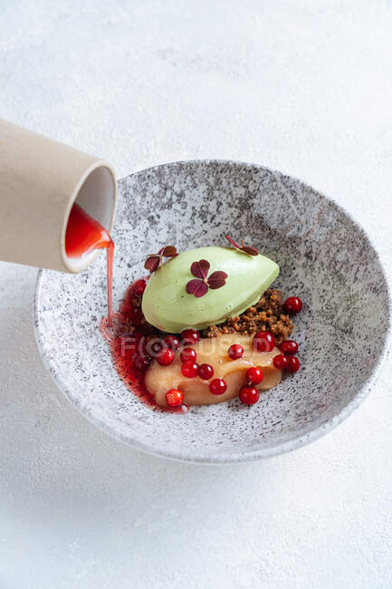 Dall'alto di ciotola elegante con fetta di pesce rosso e avocado servito con bacche rosse e versando con salsa rossa — Foto stock