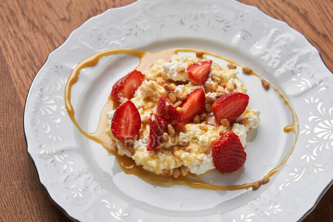 De dessus de fromage cottage sur assiette blanche servie avec des tranches de fraises rouges fraîches et du caramel — Photo de stock