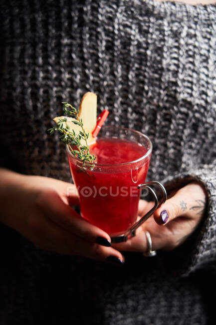 Senhora sem rosto apresentando saboroso soco vermelho em vidro — Fotografia de Stock