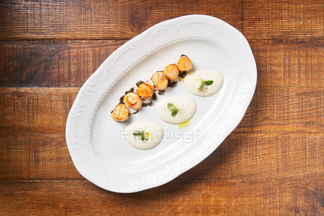 Жареные гребешки с соусом на тарелке — стоковое фото