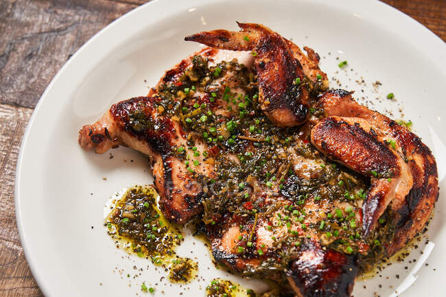 Dall'alto di pollo grigliato succoso con olio d'oliva e cipolla verde su piatto bianco in ristorante — Foto stock