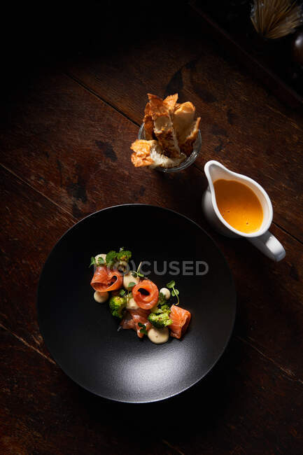 Plat élégant de haute cuisine avec saumon dans un bol noir — Photo de stock