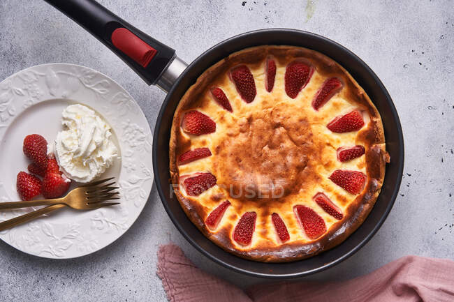 Gebackene Torte mit Erdbeere in Pfanne auf Tisch schneiden — Stockfoto