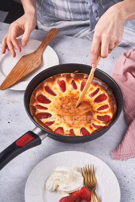 From above of faceless female confectioner cutting baked pie with strawberry in pan on table — Stock Photo