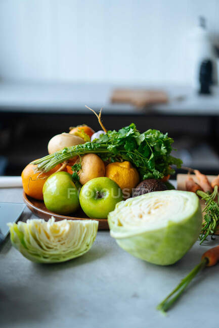 Mazzo di frutta e verdura fresca messa sul bancone durante la preparazione del pranzo nella moderna cucina — Foto stock