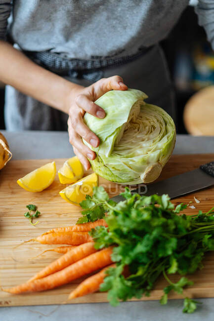 Femmina irriconoscibile che taglia cavolo maturo mentre prepara un'insalata sana per il pranzo a casa — Foto stock