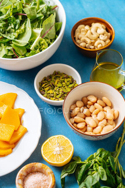 Зверху асортимент свіжих інгредієнтів для здорового вегетаріанського приготування їжі, розміщеного на синьому фоні на кухні — стокове фото