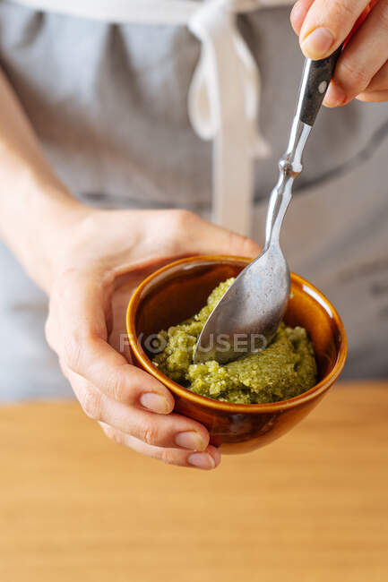 From above unrecognizable person demonstrating bowl with thick vegetarian sauce to camera while cooking in kitchen at home — Stock Photo