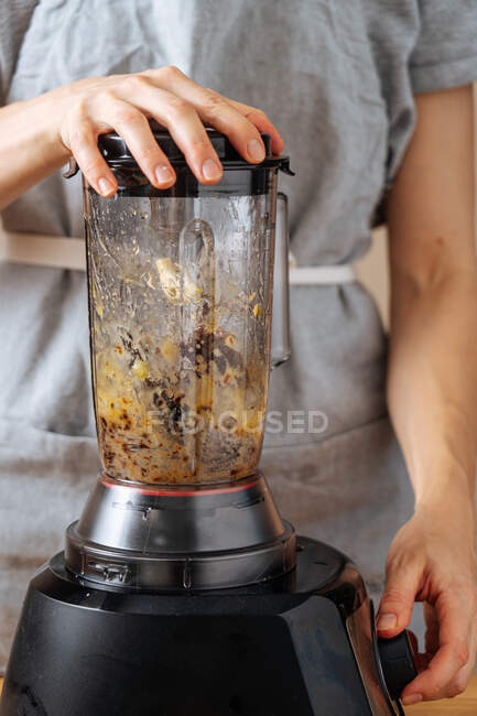 Donna irriconoscibile in grembiule con frullatore per fare la salsa mentre si prepara il pranzo in cucina a casa — Foto stock
