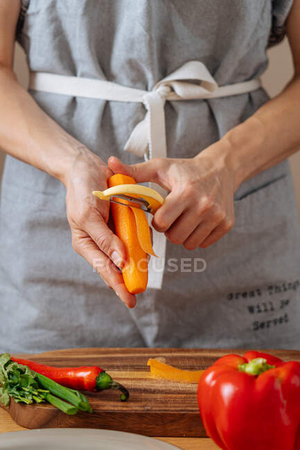 Анонимный человек режет морковку для салата — стоковое фото
