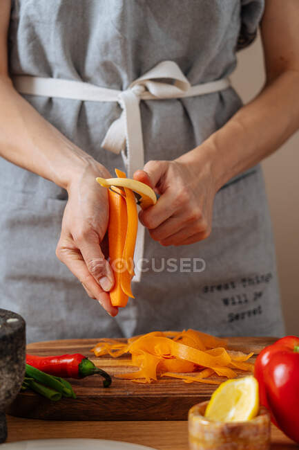 Persona anónima rebanando zanahoria para ensalada - foto de stock