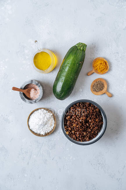 Vista dall'alto degli ingredienti per hamburger vegetariani di zucchine e lenticchie con spezie su sfondo bianco — Foto stock