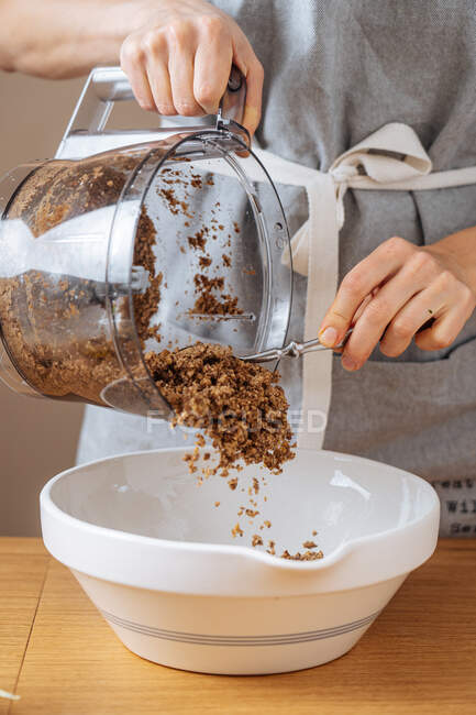 Woman putting ground ingredient into bowl — Stock Photo