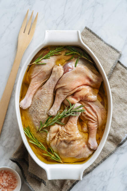 Uncooked marinated chicken legs in baking dish — Stock Photo