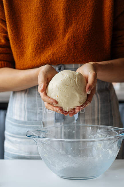 Woman with dough in hands standing at table — Stock Photo