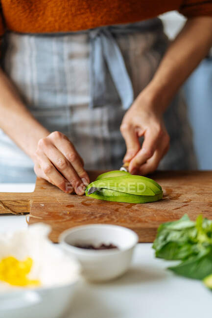 Woman cutting avocado on cutting board — Stock Photo