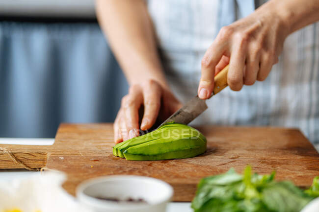 Frau schneidet Avocado auf Schneidebrett — Stockfoto