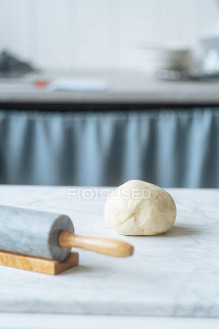 Massa de farinha amassada fresca na mesa com rolo pronto para preparar pastoso na cozinha leve — Fotografia de Stock