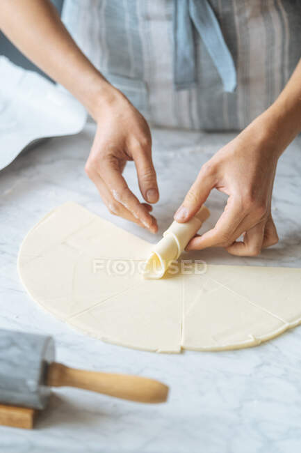Cook twisting dough into croissant on table — Stock Photo