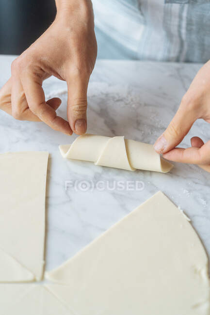 De dessus la culture cuire soigneusement rouler morceau de pâte en bagel sur la table dans la cuisine — Photo de stock