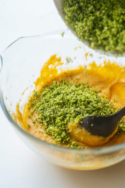 Von oben fleißig Kräuter und orangefarbene Gemüsemischung mit dem Löffel auf dem Tisch in der hellen Küche kochen — Stockfoto