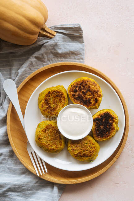 From above fried tasty appetizing cutlets in white plate with sour cream on served table with pumpkin and linen — Stock Photo